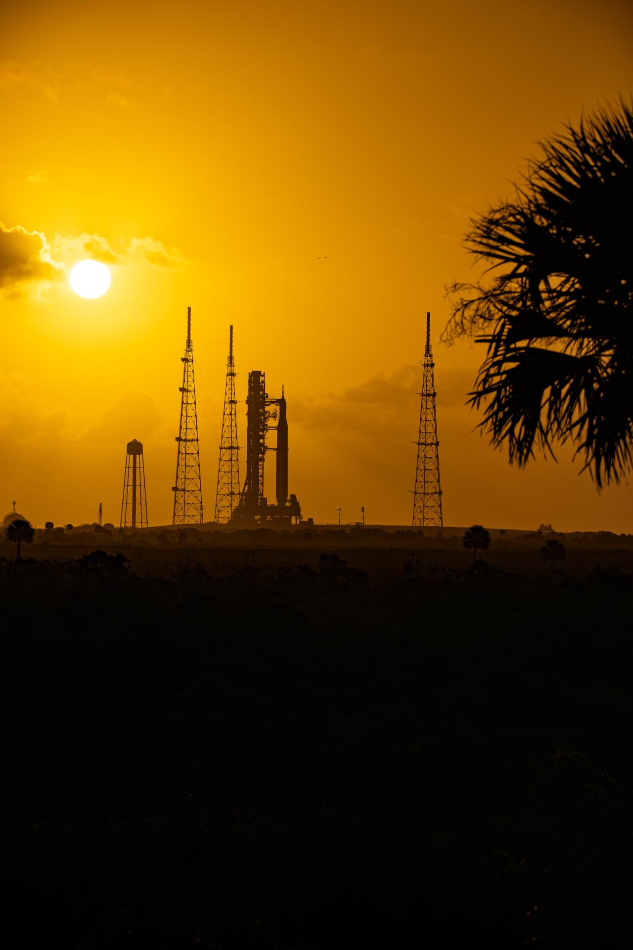 This image shows a sunset of NASA’s SLS (Space Launch System) and Orion spacecraft at NASA’s Kennedy Space Center. NASA's massive Crawler-Transporter, upgraded for the Artemis program, carried the powerful SLS rocket and Orion spacecraft on the Mobile Launcher from the Vehicle Assembly Building to Launch Pad 39B at Kennedy Space Center in preparation for the Artemis II mission.